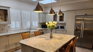Una cocina con una isla central, luces colgantes, un refrigerador y un microondas.