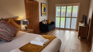 Habitación de hotel con cama, escritorio, silla, televisión y un ventanal grande.