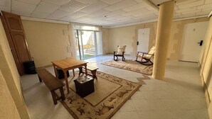 Una habitación amplia con una mesa de madera, dos sillas, un banco y una alfombra estampada.