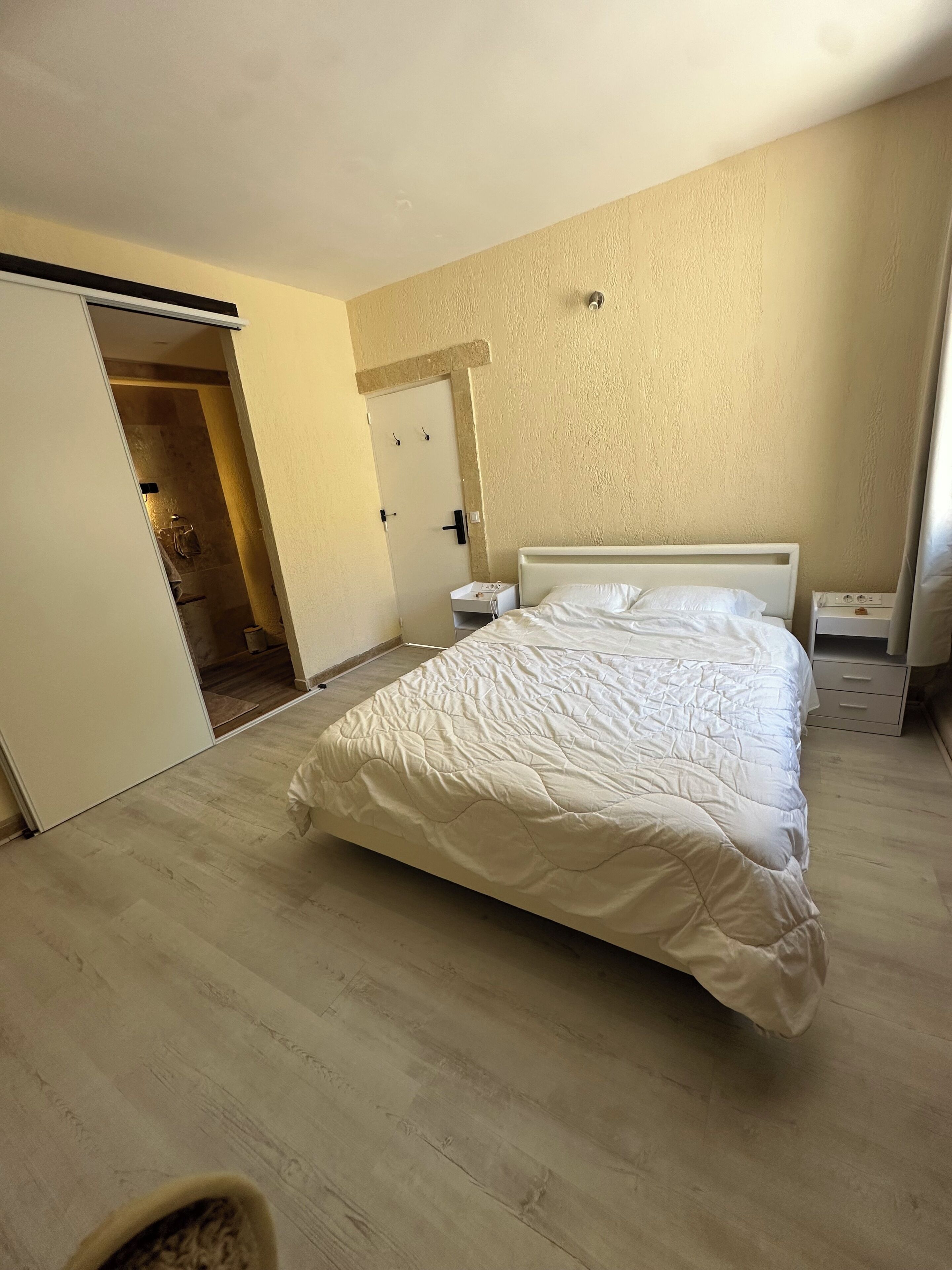 Ein Schlafzimmer mit Bett, Nachttisch, Wandheizung und einer Tür zum Badezimmer.