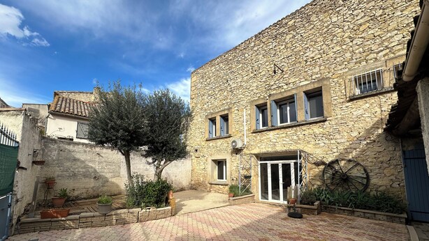 Un patio con muros de piedra, un árbol y plantas en macetas.