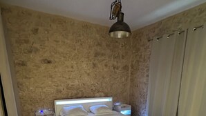 Un dormitorio con cama, mesitas de noche y una lámpara colgante.