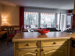 Ein Hotelzimmer mit Holztresen, Obstschale, einer Couch und Blick ins Freie.