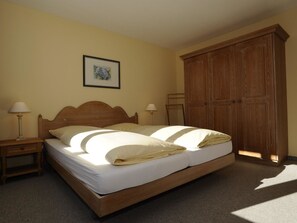 A bedroom with a wooden bed, two bedside tables with lamps, a large wardrobe, and a framed picture on the wall. - Chalchboda 1 Appartement/Fewo, Bad, WC, 4-Bettwohnung by Interhome (Arosa)