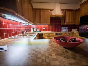 Eine Küche mit Holzausstattung, einer roten Fliesenrückwand, einer Holz Arbeitsplatte, einem Spülbecken und einer roten Schüssel auf der Arbeitsfläche.