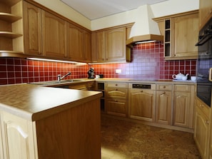 Eine Küche mit Holzausstattung, gefliestem Rücksprung und integriertem Backofen.