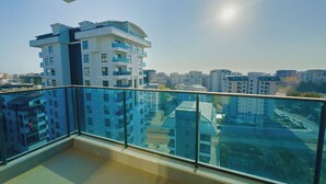 A balcony with a glass railing overlooking a cityscape with modern buildings. - "The Best Holiday Experience in Alanya & Mahmutlar." (Mahmutlar)