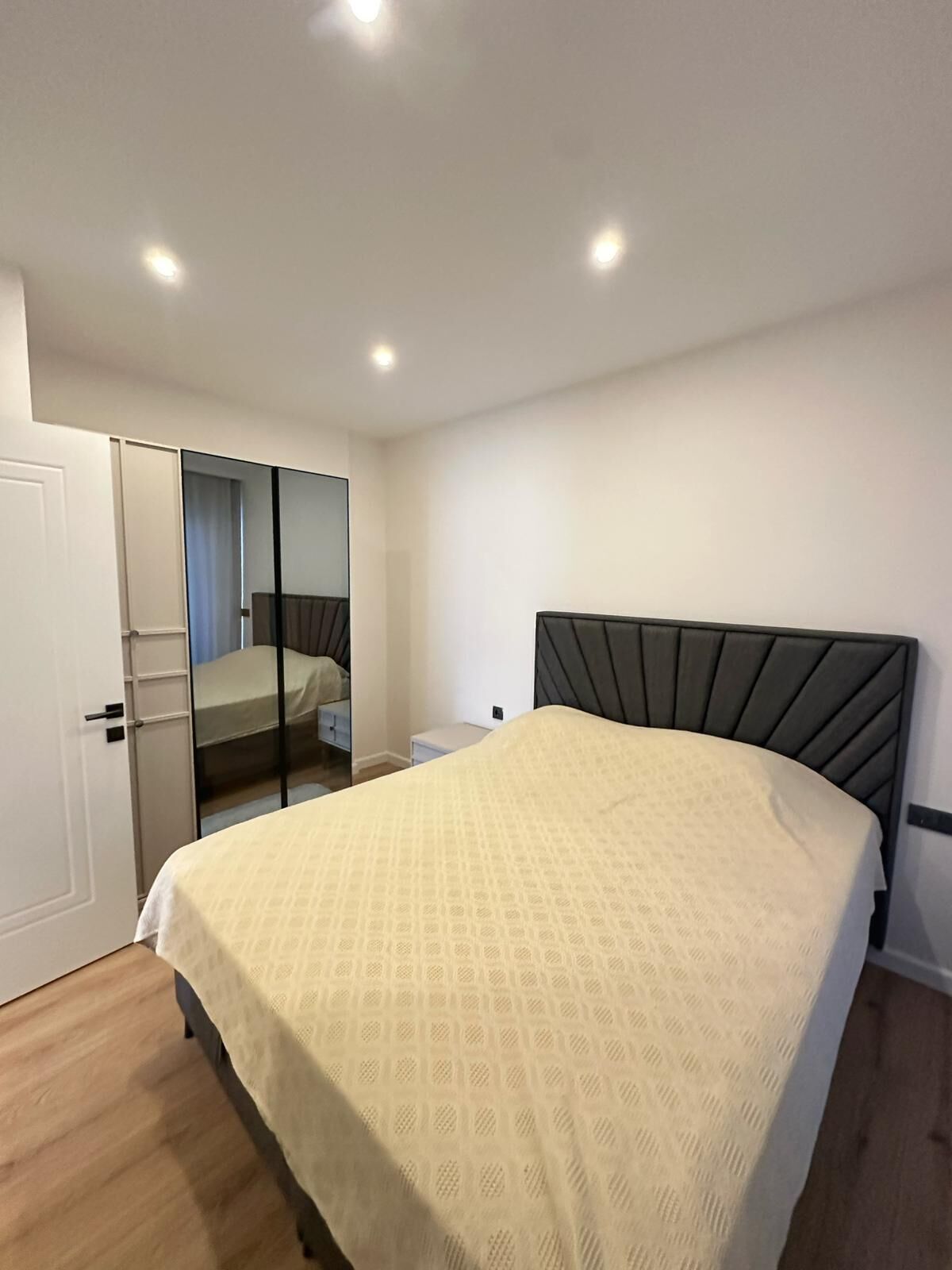 Une chambre à coucher avec un lit, une armoire, un miroir et une table de chevet.
