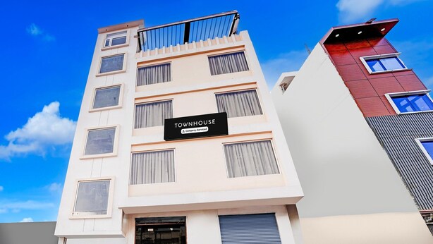 Um edifício de vários andares com uma placa que diz 'TOWNHOUSE Company-Serviced'.