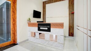 Uma mesa de recepção com uma placa indicando 'TOWNHOUSE', uma televisão montada e um painel de parede de madeira.