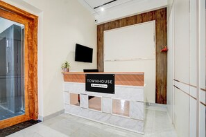 Ein Empfangsschalter mit einem Schild, das 'TOWNHOUSE' zeigt, einem angebrachten Fernseher und einer Wand aus Holzpaneelen.