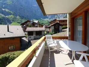 A balcony with a table and chairs, overlooking a mountainous landscape with traditional buildings. - Adlerhorst Leukerbad # 6-bed apartment, Bad, WC by Interhome (Leukerbad)