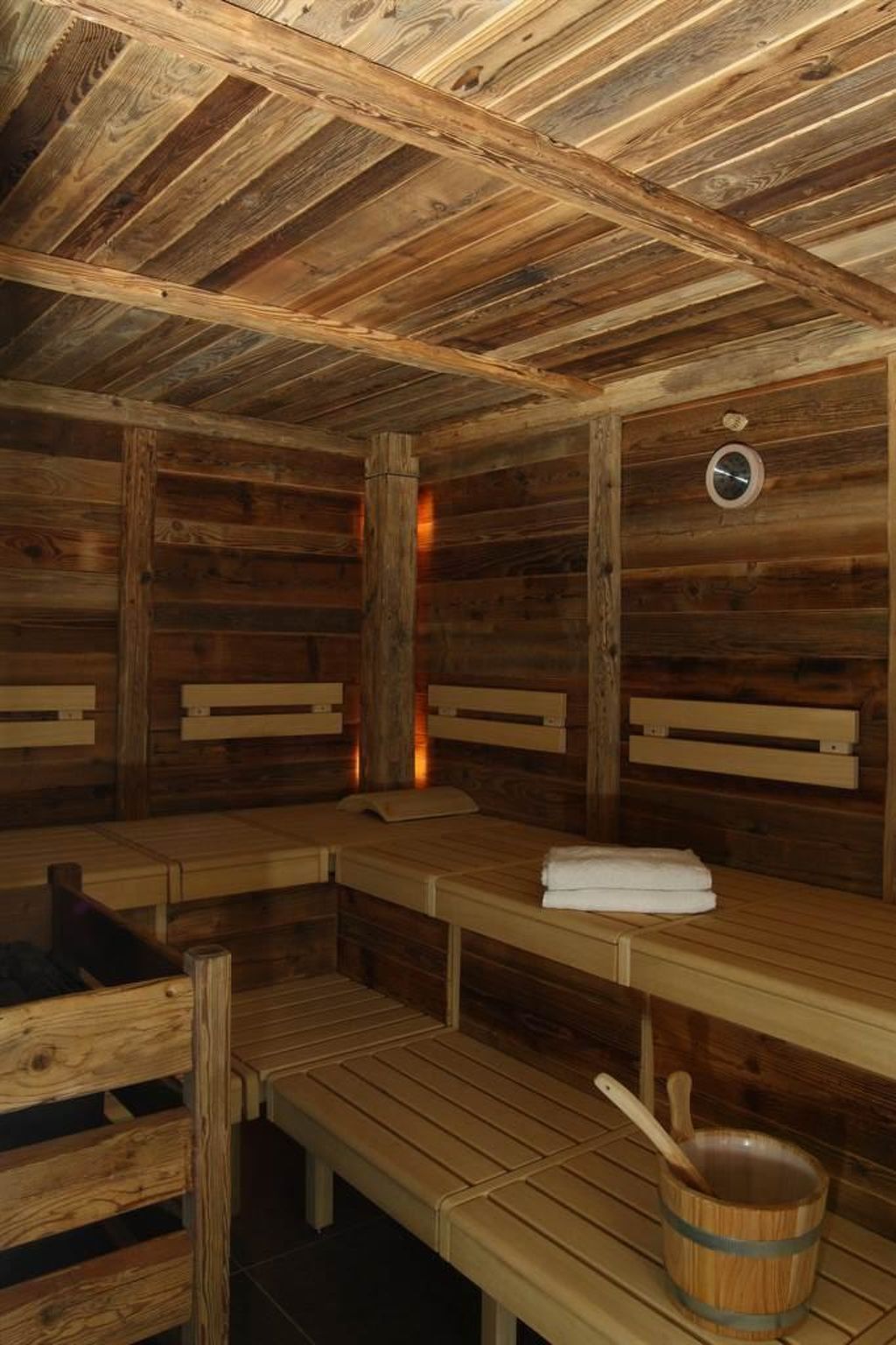 Una sauna amb grans bancs de fusta, sostre de fusta i un cubet de fusta.