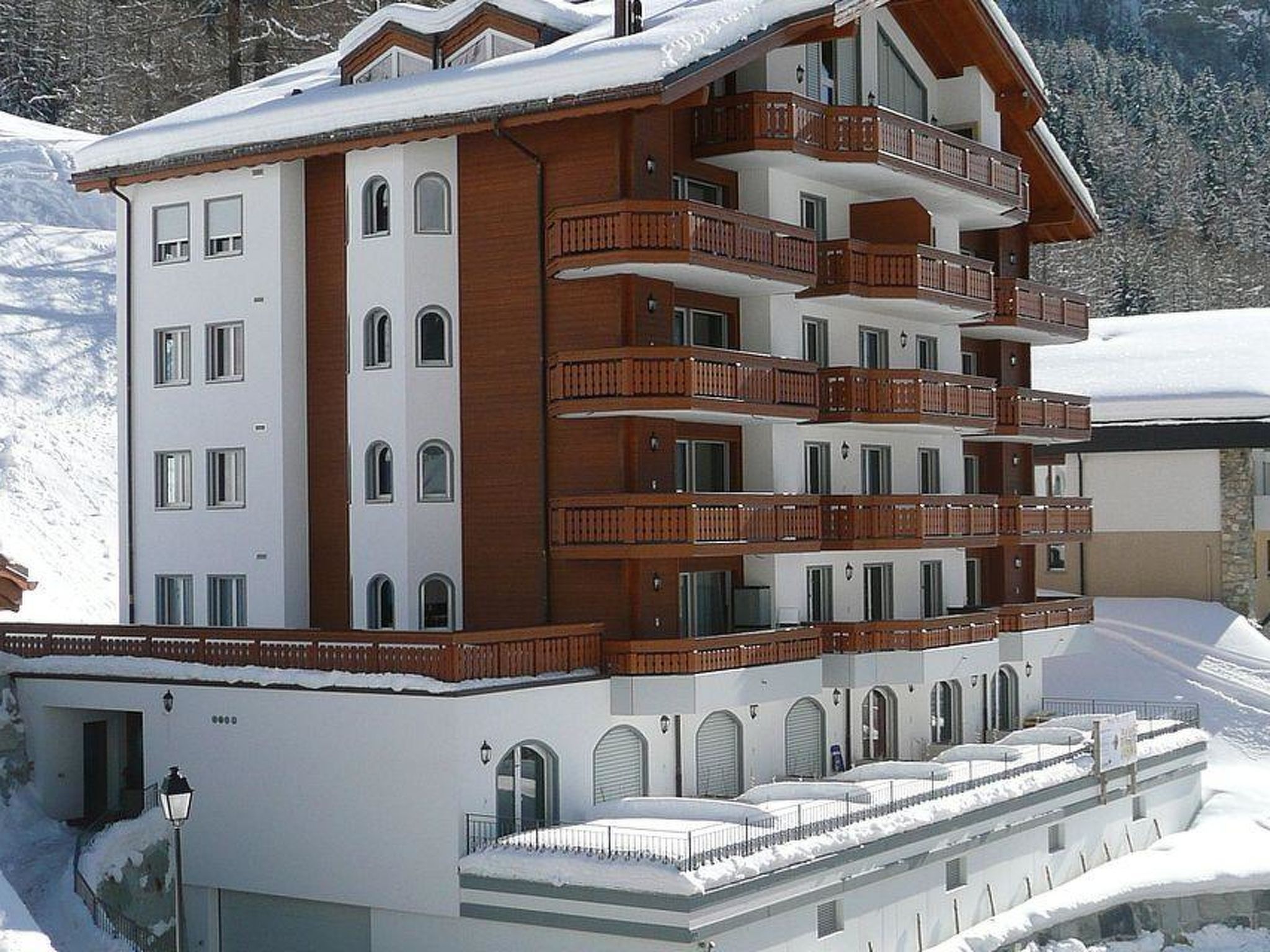 Ein mehrstöckiges Hotel mit Balkonen, Bogenfenstern und einem mit Schnee bedeckten Dach.