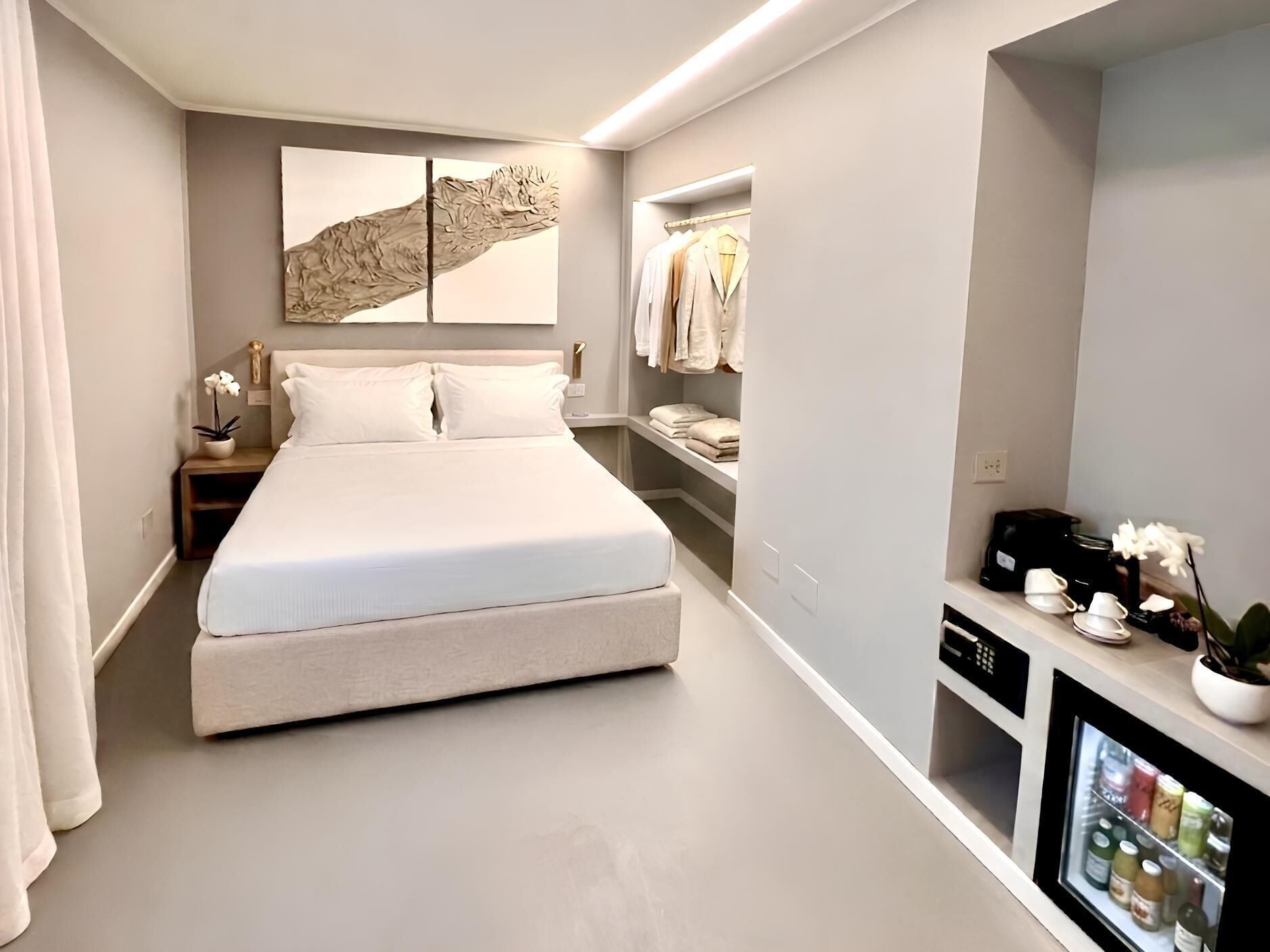 Un dormitorio moderno con una cama grande, un armario, una mesita de noche y televisión integrada.