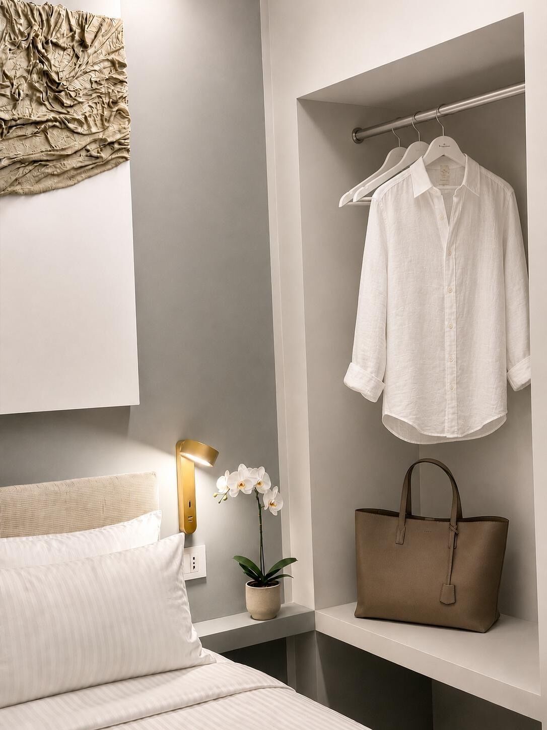 Un dormitorio moderno con una cama, una mesita de noche con lámpara, un perchero, un bolso y una estantería en la pared.