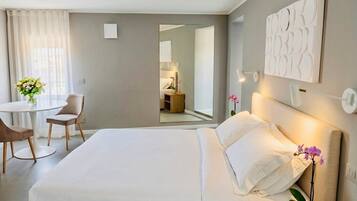 A hotel room with a bed, bedside table, lamp, and a small potted plant.