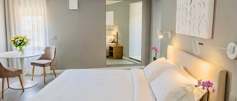 A hotel room with a bed, bedside table, lamp, and a small potted plant.