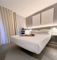 Ein modernes Hotelzimmer mit einem großen Bett, einem Nachttisch und einem Beistelltisch.