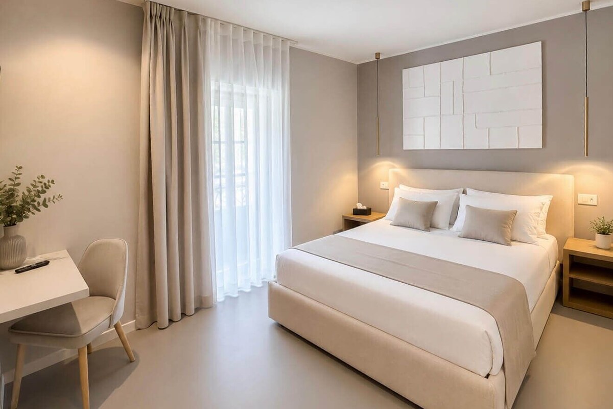 A modern bedroom with a large bed, bedside tables, a desk, and a potted plant.