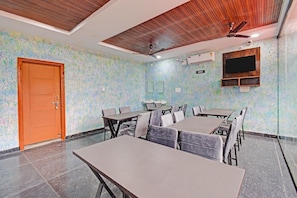 A conference room with a wooden door, a ceiling fan, and a television mounted on the wall.