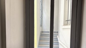 Une porte fermée avec une fenêtre, une poignée en métal et un mur à texture.