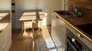 Une cuisine de taille réduite, avec une table en bois, un évier et un four encastré.