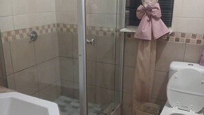 A bathroom with a shower, toilet, and bathtub.