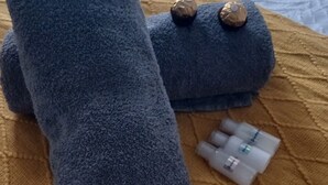 A bed with a white textured bedspread, a rolled blue towel, and a small white object on the bed. - Room-tranquil Guest Room in Randburg wit (Johannesburg)