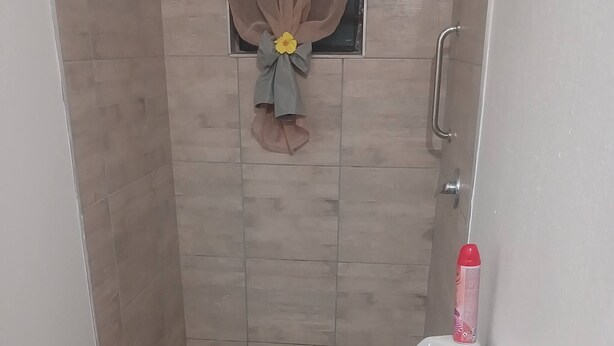 A small bathroom with a toilet, a shower, a checkered floor, and a towel hanging on the wall. - Room-tranquil Guest Room in Randburg wit (Johannesburg)