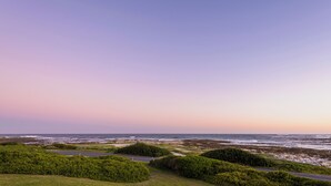 A coastal landscape with a road, greenery, and the ocean. - Rustic 3 Bedroom Beach Cottage, perfect for a peaceful getaway. (Birkenhead, Gansbaai)