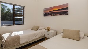 A bedroom with a bed, a nightstand, a lamp, a window with blinds, and a painting on the wall. - Rustic 3 Bedroom Beach Cottage, perfect for a peaceful getaway. (Birkenhead, Gansbaai)