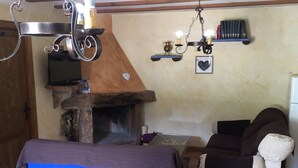 Un saló amb una llar de pedra, una televisió, un sofà i una cadira.