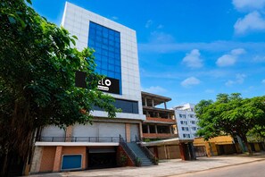 A modern building with a large glass facade, a sign indicating a service area, and a staircase leading to an upper level. - Hotel O Bhangagarh (Guwahati)