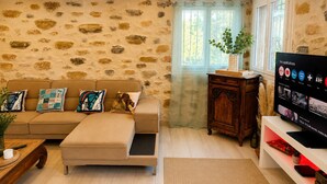 Ein Wohnzimmer mit Steinwand, einer Couch mit Kissen, einem Holzkabinett und einem Fernseher, der Apps anzeigt.