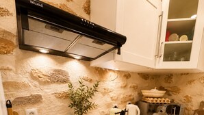 Eine Küche mit weißen Schränken, einem schwarzen Induktionskochfeld, einem Edelstahlbackofen, einer eingebauten Mikrowelle und einer Spritzschutzleiste mit Steinoptik.