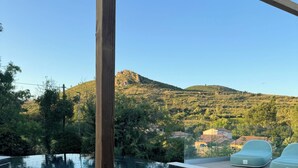 Ein Pool mit Blick auf einen Berg, ein Holzpfosten und ein grüner Stuhl.
