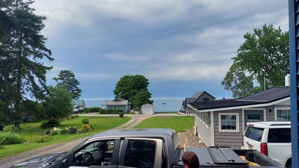 A residential area with houses, a driveway, and a body of water in the background.