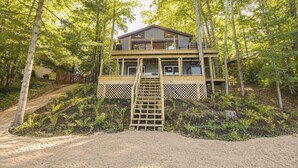 A two-story wooden cabin with a wooden deck and a ladder leading to the entrance. - Scandinavian Cabin on Sandy Lakefront [NEW RENOVATION] (Lake Ann)