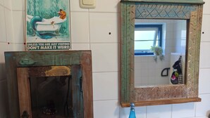 Een badkamer met een vintage spiegel, een decoratief bord en toiletartikelen op het aanrecht.