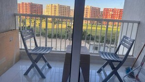Ein Balkon mit zwei Stühlen, einem Tisch und Blick auf hohe Gebäude.