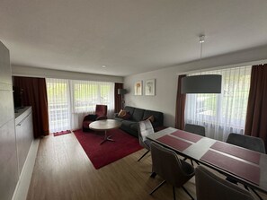 Ein modernes Wohnzimmer mit einer Couch, einem runden Couchtisch und einem Esstisch mit Stühlen.