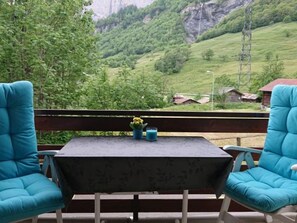 A balcony with a table and two chairs, overlooking a green valley with houses and a mountain in the background. - Valère C 211 # 6-bed apartment, Dusche, WC 6-Bettwohnung, Dusche, WC by Interhome (Leukerbad)