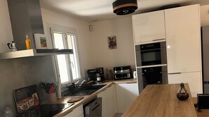 A modern kitchen with white cabinetry, a wooden countertop, and stainless steel appliances. - A comfortable home between Aix-en-Provence, Marseille, and the Côte Bleue (Saint-Victoret)