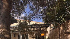 An outdoor seating area with tables and chairs, surrounded by trees and a building with a tiled roof. - A comfortable home between Aix-en-Provence, Marseille, and the Côte Bleue (Saint-Victoret)