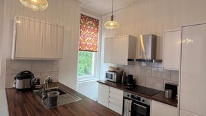 A modern kitchen with wooden countertops, stainless steel appliances, and pendant lighting. - O Romeo Suite at Elmwood House (Nottingham)