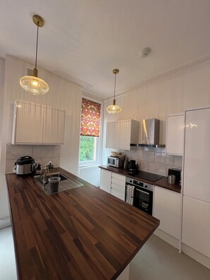 A modern kitchen with wooden countertops, stainless steel appliances, and pendant lighting. - O Romeo Suite at Elmwood House (Nottingham)