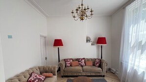 A living room with two sofas, a coffee table, a chandelier, and a large window with sheer curtains. - O Romeo Suite at Elmwood House (Nottingham)