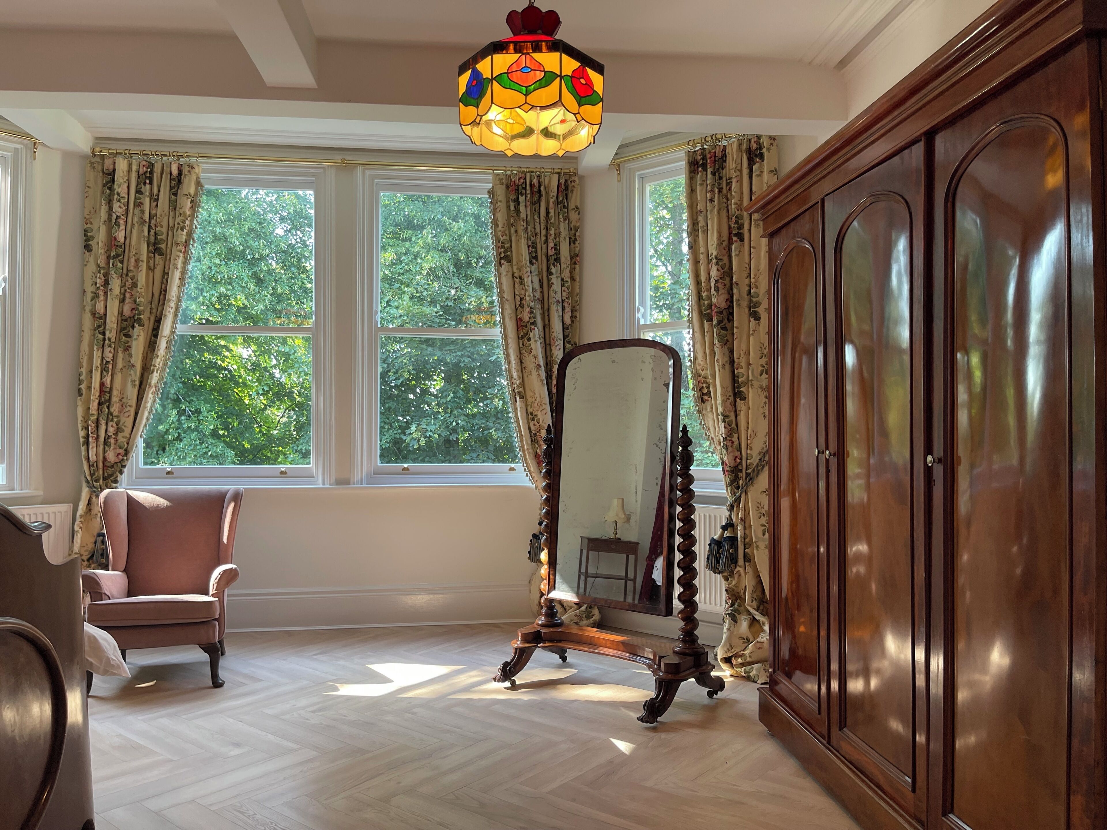 Une pièce avec un grand miroir, une armoire en bois et une chaise.