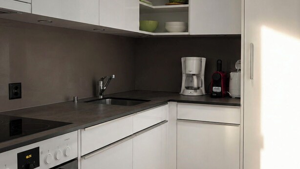 A modern kitchen with white cabinetry, a built-in oven, a coffee maker, and a microwave. - Majesta Leukerbad # 6-bed apartment, Dusche, WC by Interhome (Leukerbad)